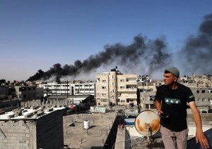 Un uomo osserva il fumo nero e denso che si leva dall&#039;incendio di un edificio causato dai bombardamenti israeliani a Rafah, nel sud della Striscia di Gaza, il 10 maggio 2024